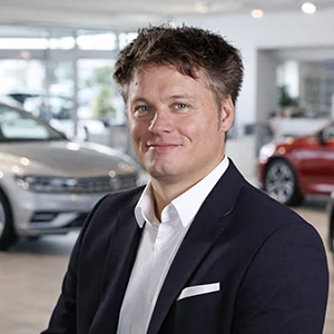 Mitarbeiter im Autohaus Ebbinghaus lächelt vor Fahrzeugen im Showroom