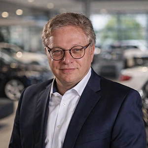 Mitarbeiter im Autohaus Ebbinghaus lächelt vor Fahrzeugen im Showroom