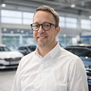 Mitarbeiter im Autohaus Ebbinghaus lächelt vor Fahrzeugen im Showroom