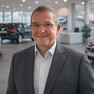 Mitarbeiter im Autohaus Ebbinghaus lächelt vor Fahrzeugen im Showroom